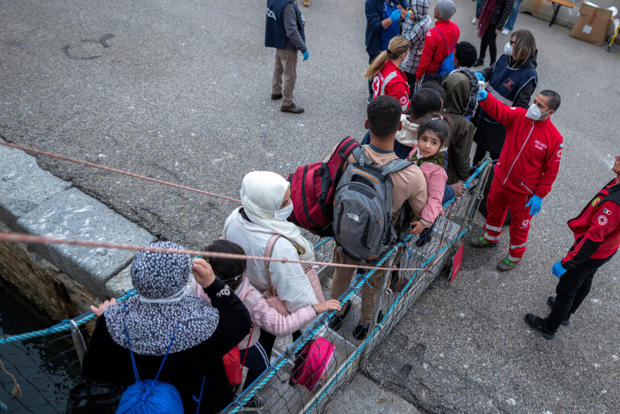 Gerettete von oben fotografiert als sie von Bord der Humanity 1 gehen und von Personal des Roten Kreuzes empfangen werden.